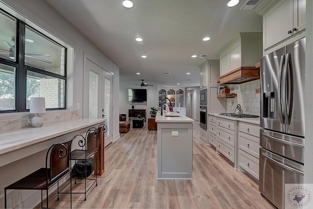 kitchen featuring appliances with stainless steel finishes, sink, white cabinetry, an island with sink, and decorative backsplash