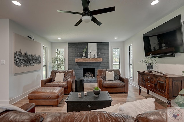 living room featuring ceiling fan, a brick fireplace, and light hardwood / wood-style floors