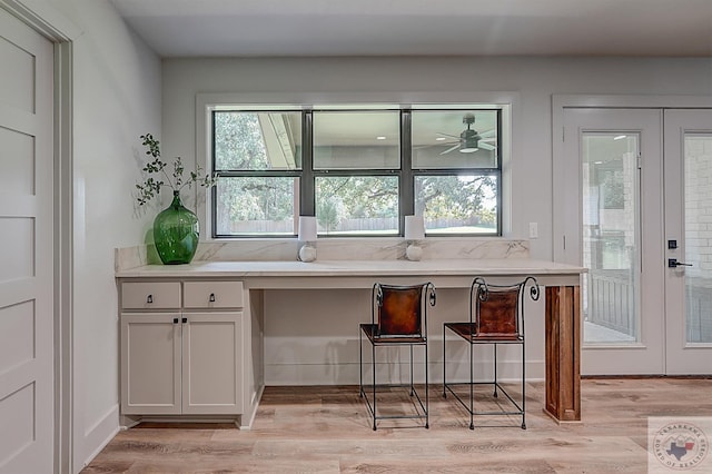 kitchen with plenty of natural light, french doors, white cabinets, and built in desk