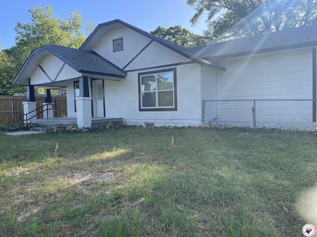 401 S State Line Ave, Texarkana, AR 71854 - view of front of home with fence, a front lawn, stucco siding, a porch, and roof with shingles