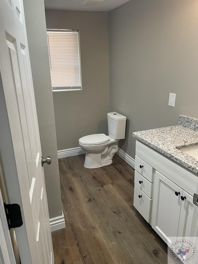 bathroom featuring wood-type flooring, toilet, and vanity