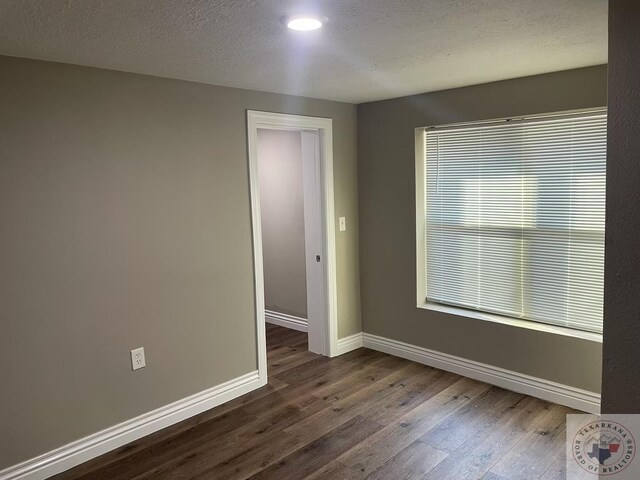 spare room featuring a textured ceiling and dark hardwood / wood-style flooring