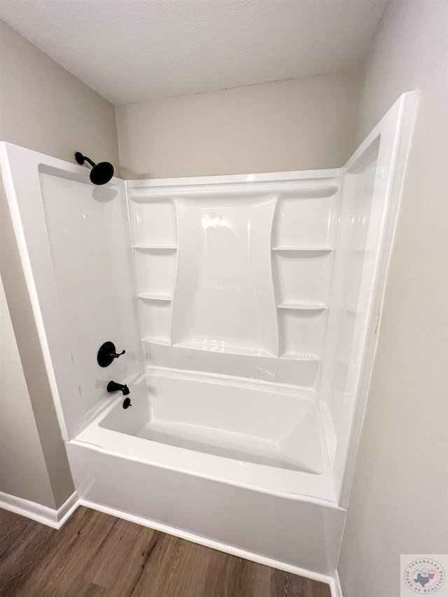 bathroom featuring hardwood / wood-style flooring, shower / washtub combination, and a textured ceiling