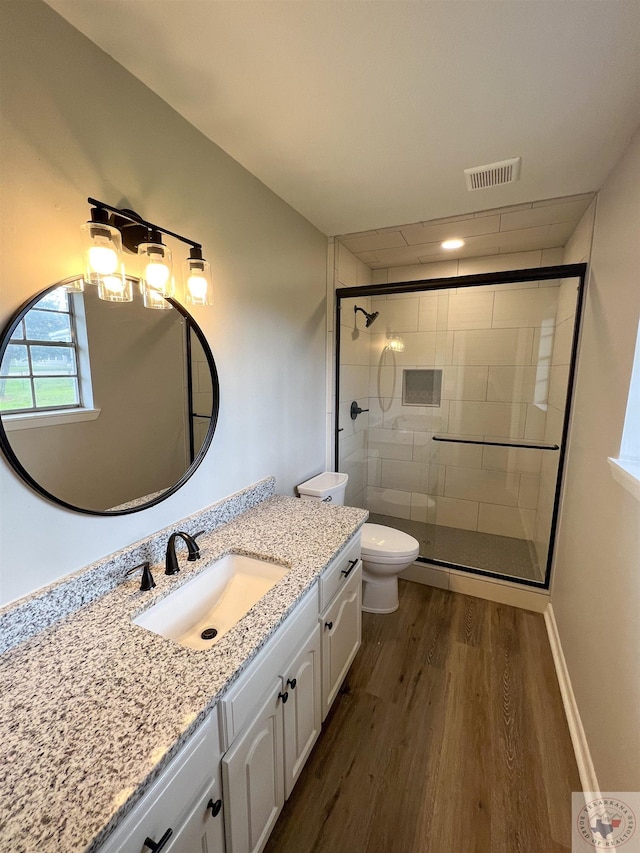 bathroom featuring wood-type flooring, toilet, an enclosed shower, and vanity