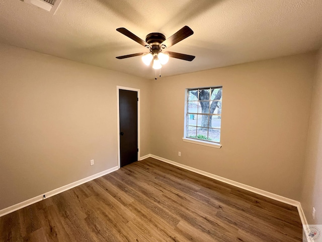 empty room with ceiling fan, dark hardwood / wood-style floors, and a textured ceiling