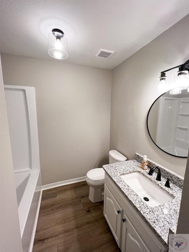 bathroom featuring vanity, hardwood / wood-style floors, a textured ceiling, and toilet