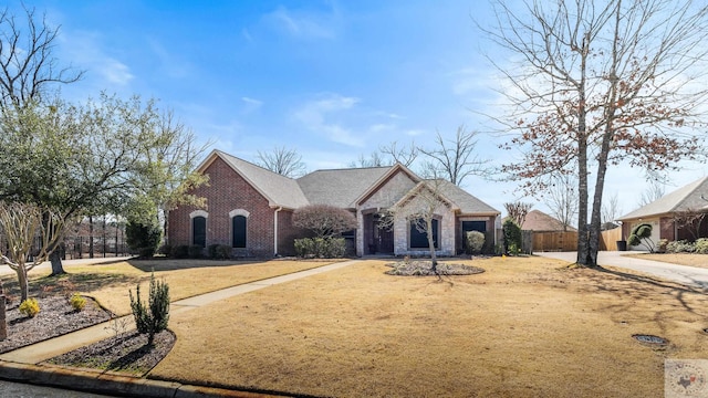 french country inspired facade with stone siding, fence, and brick siding