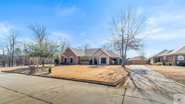 view of front facade with driveway, stone siding, fence, and brick siding