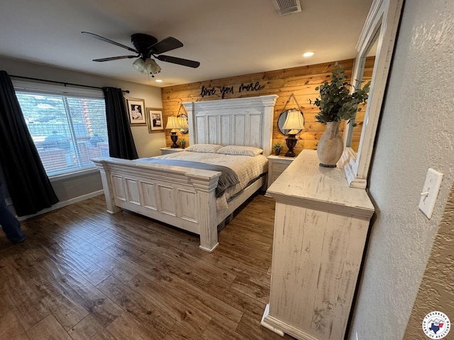 6515 N Kings Hwy, Texarkana, TX 75503 - bedroom featuring wood walls, dark wood-type flooring, a textured wall, a ceiling fan, and baseboards