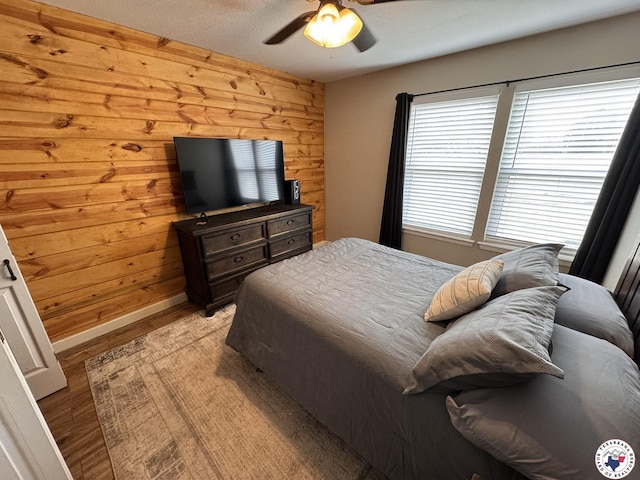 6515 N Kings Hwy, Texarkana, TX 75503 - bedroom with light wood-style floors, wooden walls, baseboards, and ceiling fan