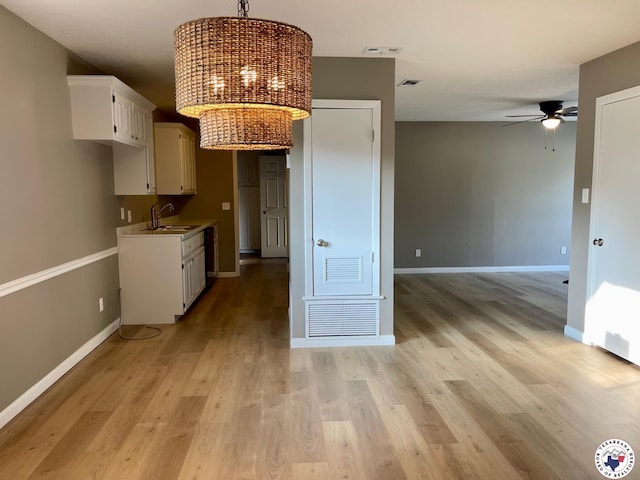 1 Sidney Dr, Texarkana, TX 75503 - kitchen featuring a chandelier, ceiling fan, baseboards, light wood-type flooring, and white cabinets