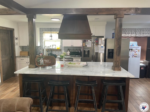 24075 US Highway 59 N, Queen City, TX 75551 - kitchen featuring custom exhaust hood, white cabinetry, light wood-type flooring, stainless steel fridge with ice dispenser, and light stone counters