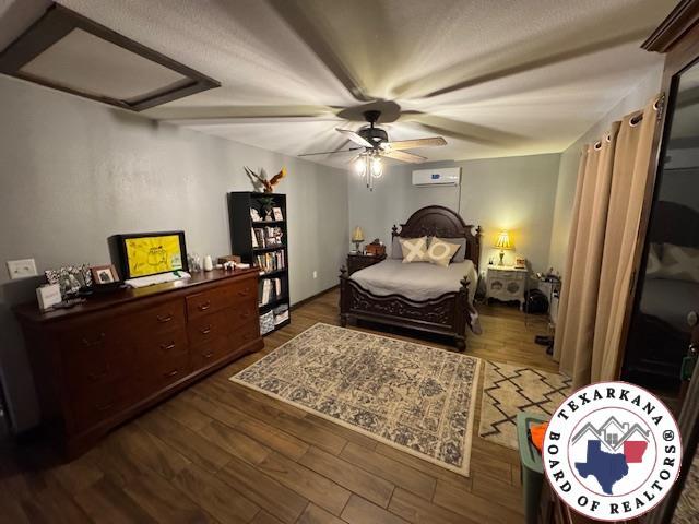 24075 US Highway 59 N, Queen City, TX 75551 - bedroom featuring a wall unit AC, dark wood-style flooring, attic access, and ceiling fan