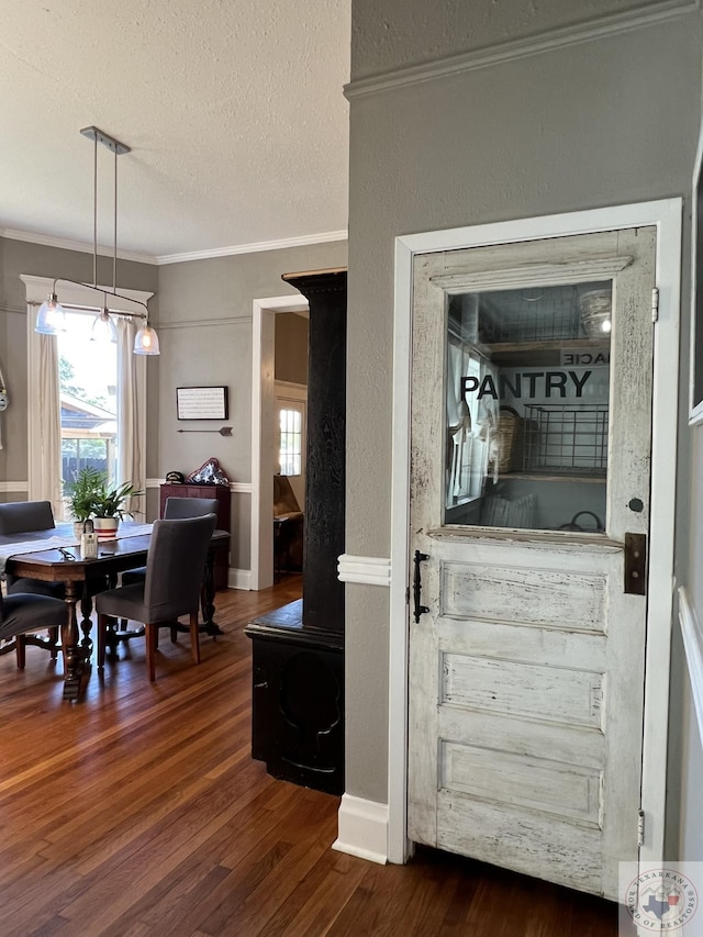 interior space with dark wood-type flooring, a textured ceiling, and ornamental molding