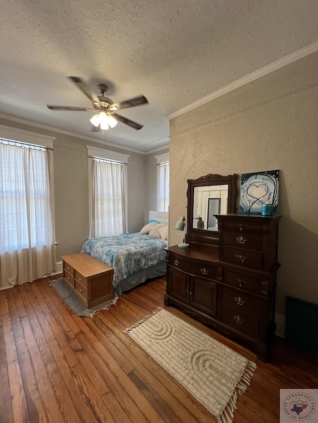 bedroom with ceiling fan, multiple windows, a textured ceiling, and hardwood / wood-style flooring