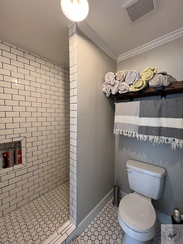 bathroom with a tile shower, toilet, and ornamental molding