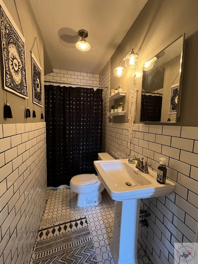 bathroom featuring toilet, a textured ceiling, tile walls, tile patterned flooring, and a shower with shower curtain