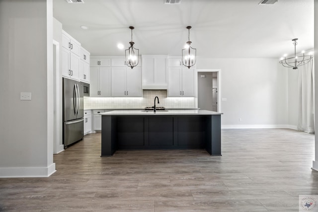 kitchen featuring stainless steel appliances, light countertops, an island with sink, and an inviting chandelier