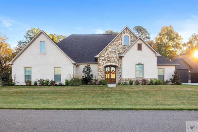 view of front of property with stone siding, a front yard, and french doors