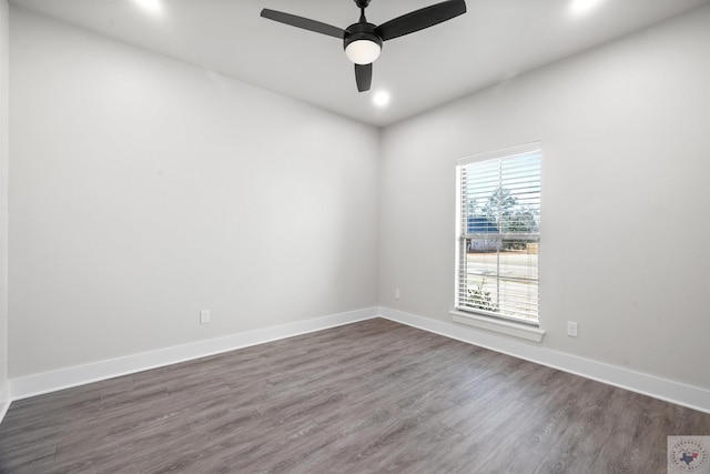 spare room with dark wood-type flooring, a ceiling fan, and baseboards