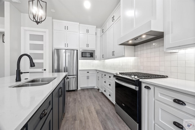 kitchen featuring light stone counters, stainless steel appliances, white cabinetry, pendant lighting, and a sink