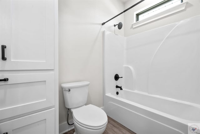 bathroom featuring wood finished floors, shower / tub combination, and toilet