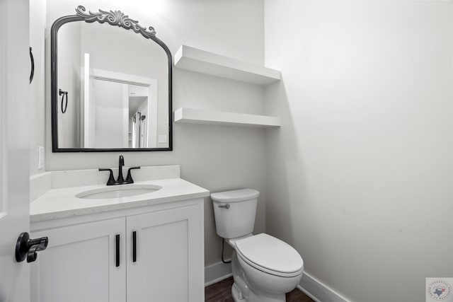 bathroom featuring toilet, wood finished floors, vanity, and baseboards