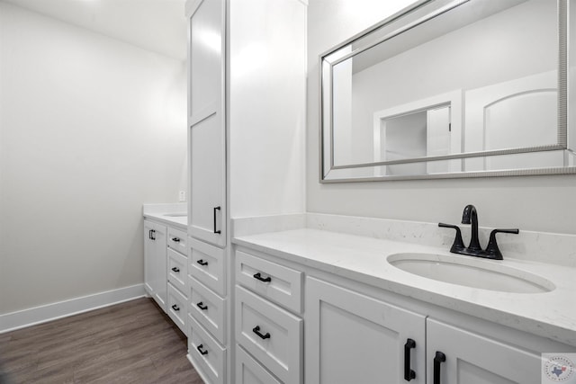 bathroom with baseboards, wood finished floors, and vanity