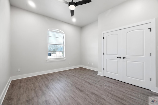 unfurnished bedroom featuring ceiling fan, a closet, wood finished floors, and baseboards