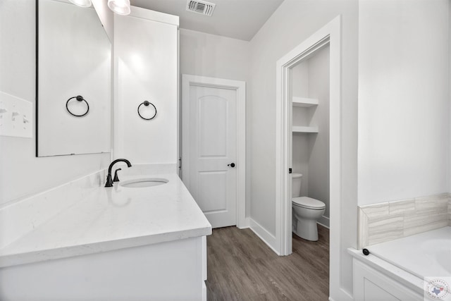 full bath with visible vents, toilet, vanity, wood finished floors, and baseboards