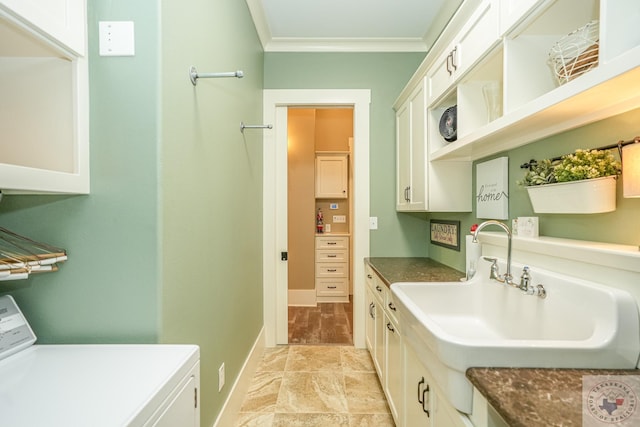 kitchen featuring ornamental molding, washer / dryer, sink, and white cabinets