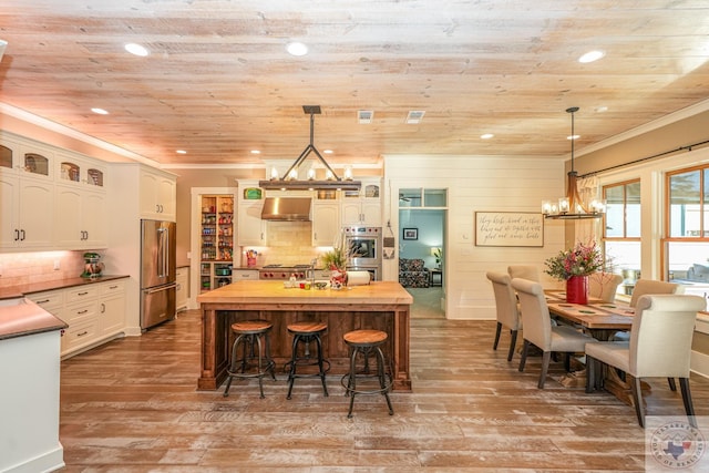 kitchen with extractor fan, appliances with stainless steel finishes, white cabinets, hanging light fixtures, and wood ceiling