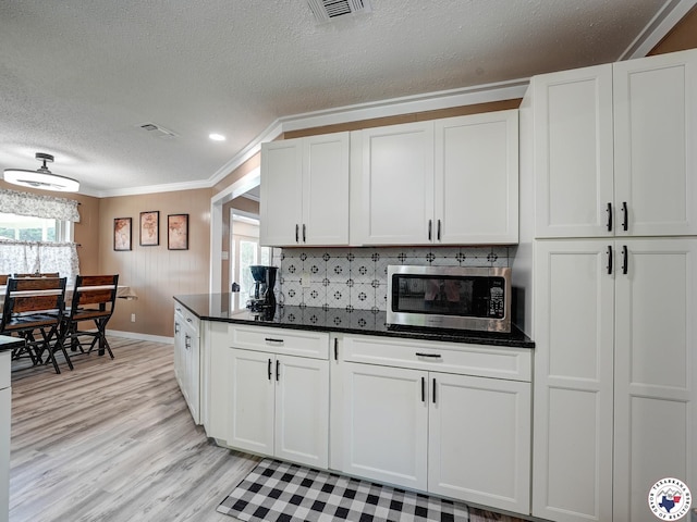 1216 Lavaca Ave, Texarkana, TX 75503 - kitchen with stainless steel microwave, ornamental molding, light wood-style flooring, a textured ceiling, and dark countertops