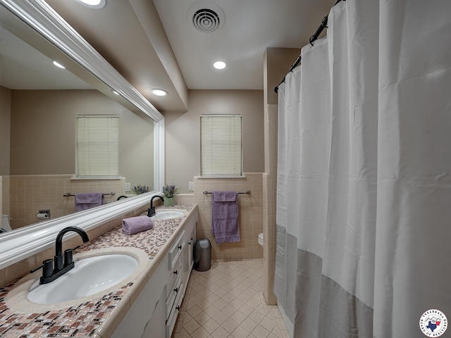 1216 Lavaca Ave, Texarkana, TX 75503 - bathroom with tile walls, tile patterned floors, double vanity, a wainscoted wall, and recessed lighting