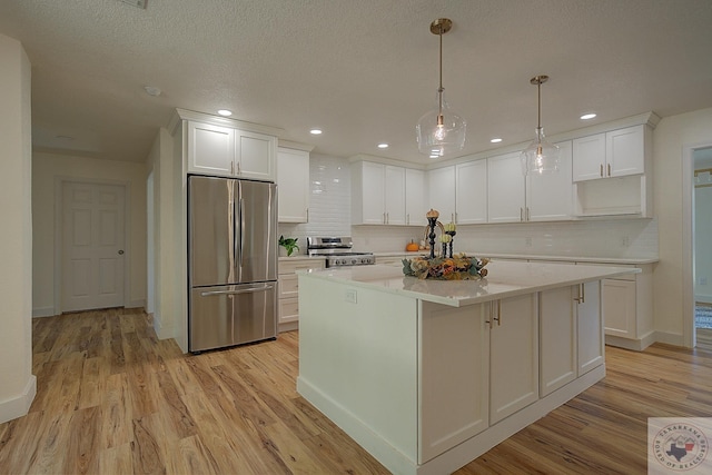 kitchen featuring light hardwood / wood-style flooring, pendant lighting, appliances with stainless steel finishes, white cabinets, and a center island