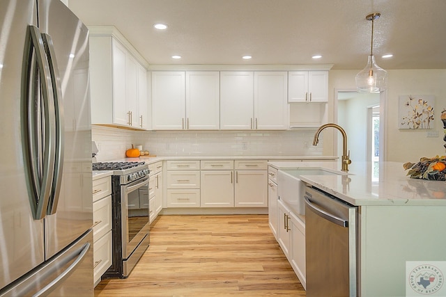 kitchen featuring white cabinetry, sink, hanging light fixtures, and stainless steel appliances