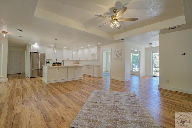 kitchen with a tray ceiling, a kitchen island, and stainless steel fridge