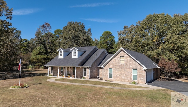 view of front of house featuring covered porch, a garage, and a front lawn