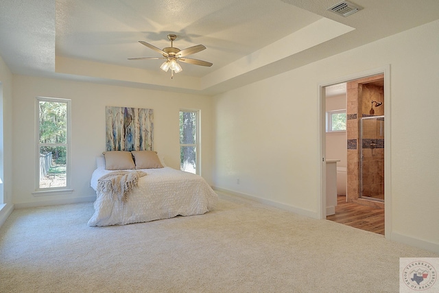 bedroom with ceiling fan, a tray ceiling, and light carpet