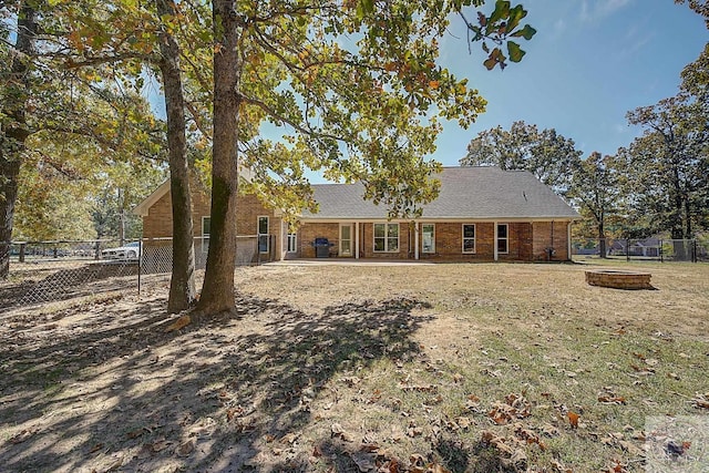 rear view of house featuring an outdoor fire pit and a lawn