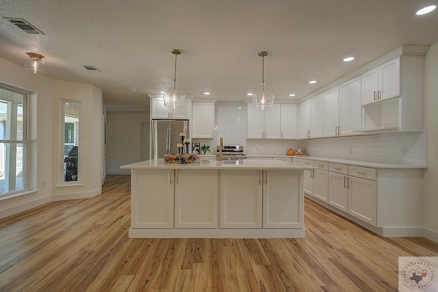 kitchen with light hardwood / wood-style floors, white cabinetry, and appliances with stainless steel finishes