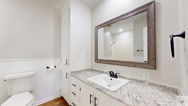 bathroom with hardwood / wood-style flooring, toilet, vanity, and walk in shower