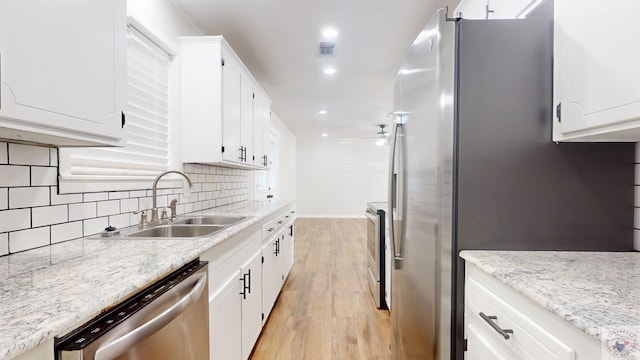 kitchen with light stone countertops, sink, white cabinetry, and stainless steel appliances