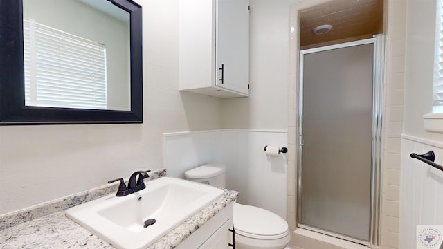 bathroom featuring toilet, a shower with door, and vanity