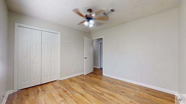 unfurnished bedroom featuring ceiling fan, light hardwood / wood-style floors, a textured ceiling, and a closet