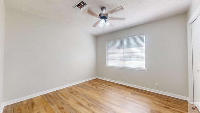 spare room featuring light wood-type flooring, a textured ceiling, and ceiling fan