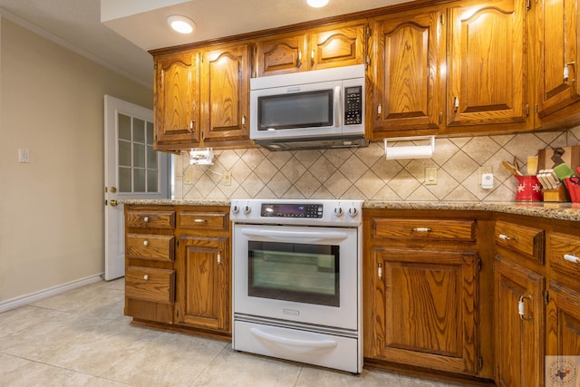 kitchen featuring stainless steel appliances, decorative backsplash, light stone counters, light tile patterned floors, and crown molding