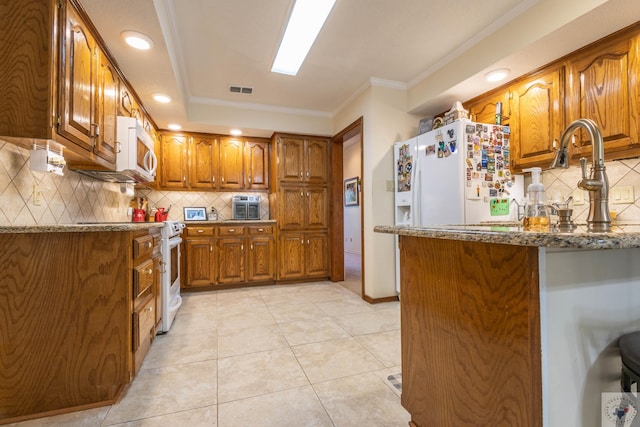 kitchen featuring stone countertops, tasteful backsplash, light tile patterned flooring, white appliances, and ornamental molding