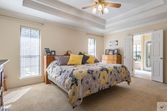 bedroom with crown molding, ceiling fan, a raised ceiling, multiple windows, and light colored carpet