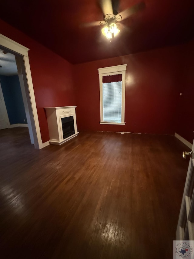 unfurnished living room featuring ceiling fan and dark wood-type flooring